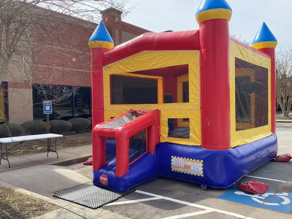 Red and yellow castle bounce house set up outside a building in Douglasville, Georgia for an event provided by Marques Amusement Company