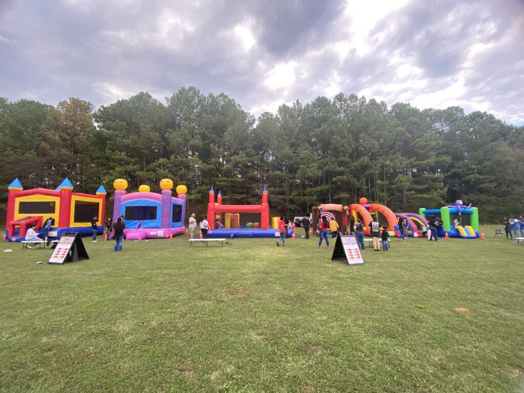 Large community event with multiple bounce house rentals set up in College Park, GA by Marques Amusement Company