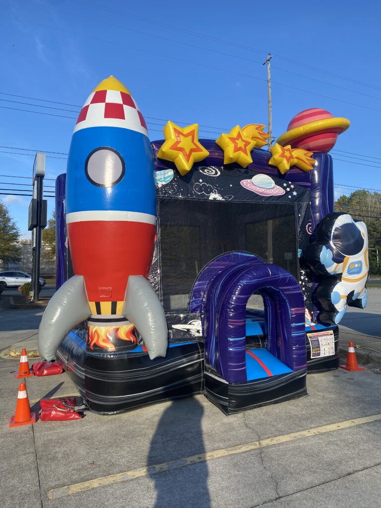 Space-themed bounce house rental with rocket and astronaut set up in College Park, GA by Marques Amusement Company