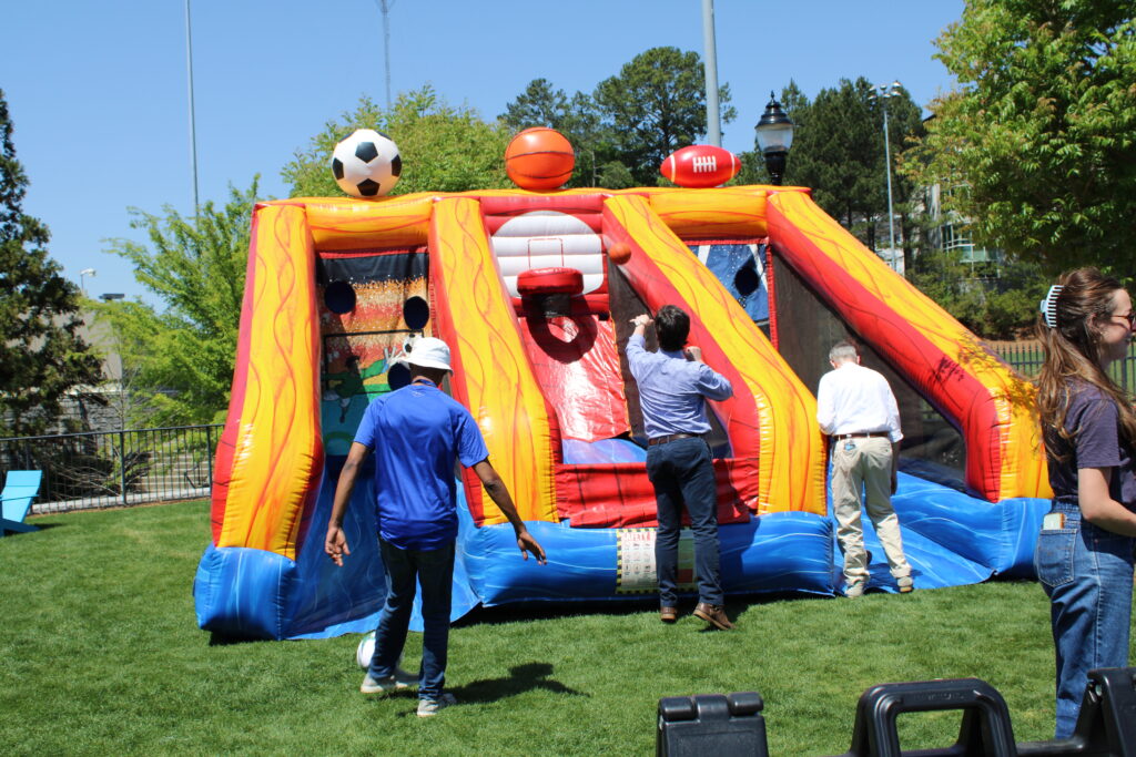 Guests playing an interactive inflatable sports game at an outdoor event in Austell, Georgia