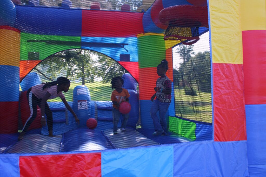 Children playing inside a colorful bounce house rentals with inflatable basketball hoops at an outdoor party in Douglasville, Georgia provided by Marques Amusement Company