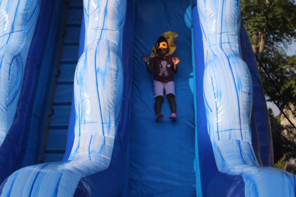 Child sliding down a large inflatable water slide at an outdoor party in Douglasville, Georgia provided by Marques Amusement Company