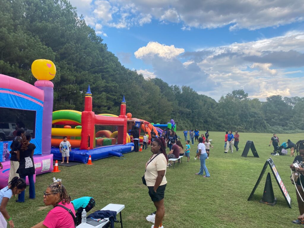 Families enjoying bounce houses and inflatable obstacle courses at an outdoor community event in Marietta, Georgia